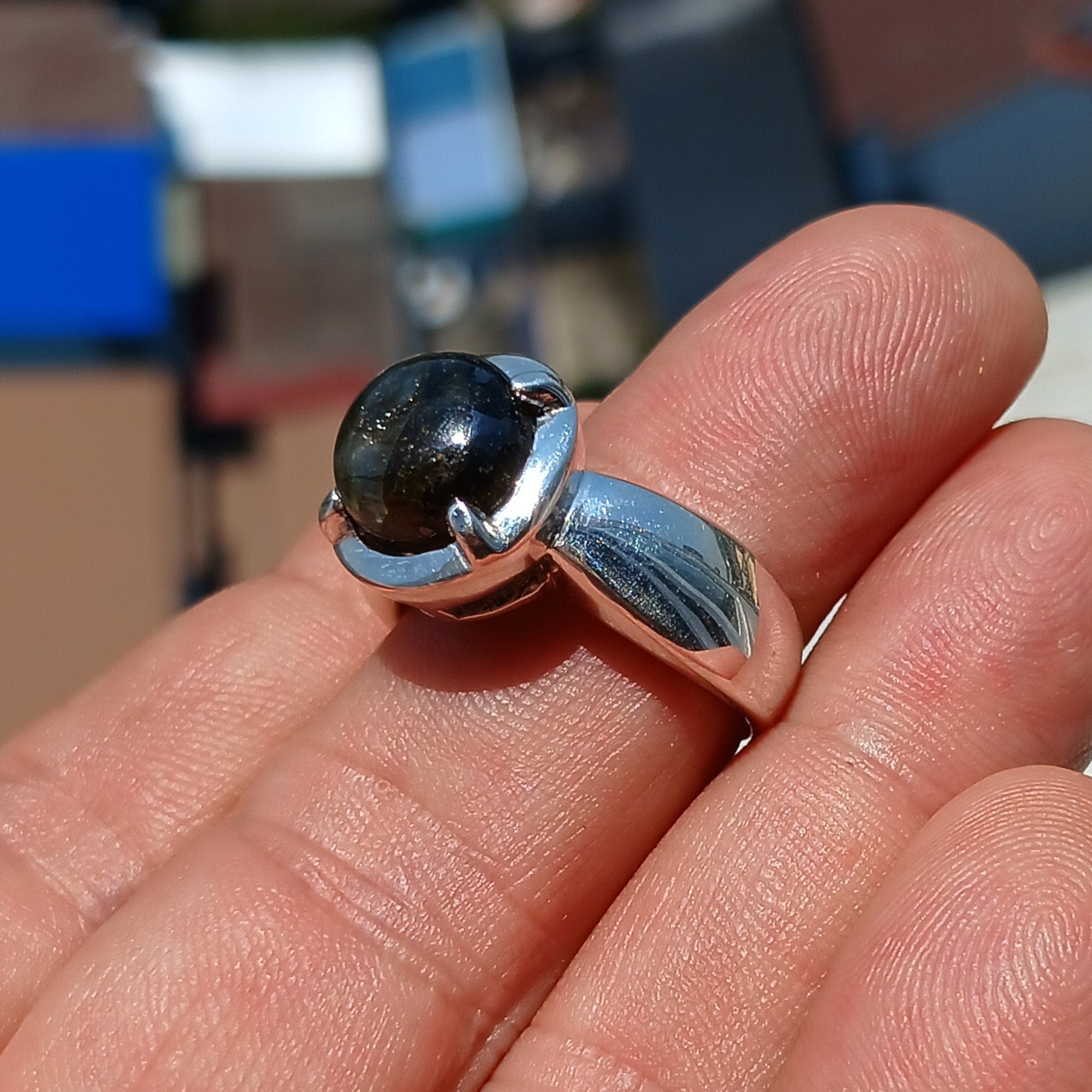 A handcrafted sterling silver ring featuring a round dark Labradorite stone, showcasing its unique design and craftsmanship.