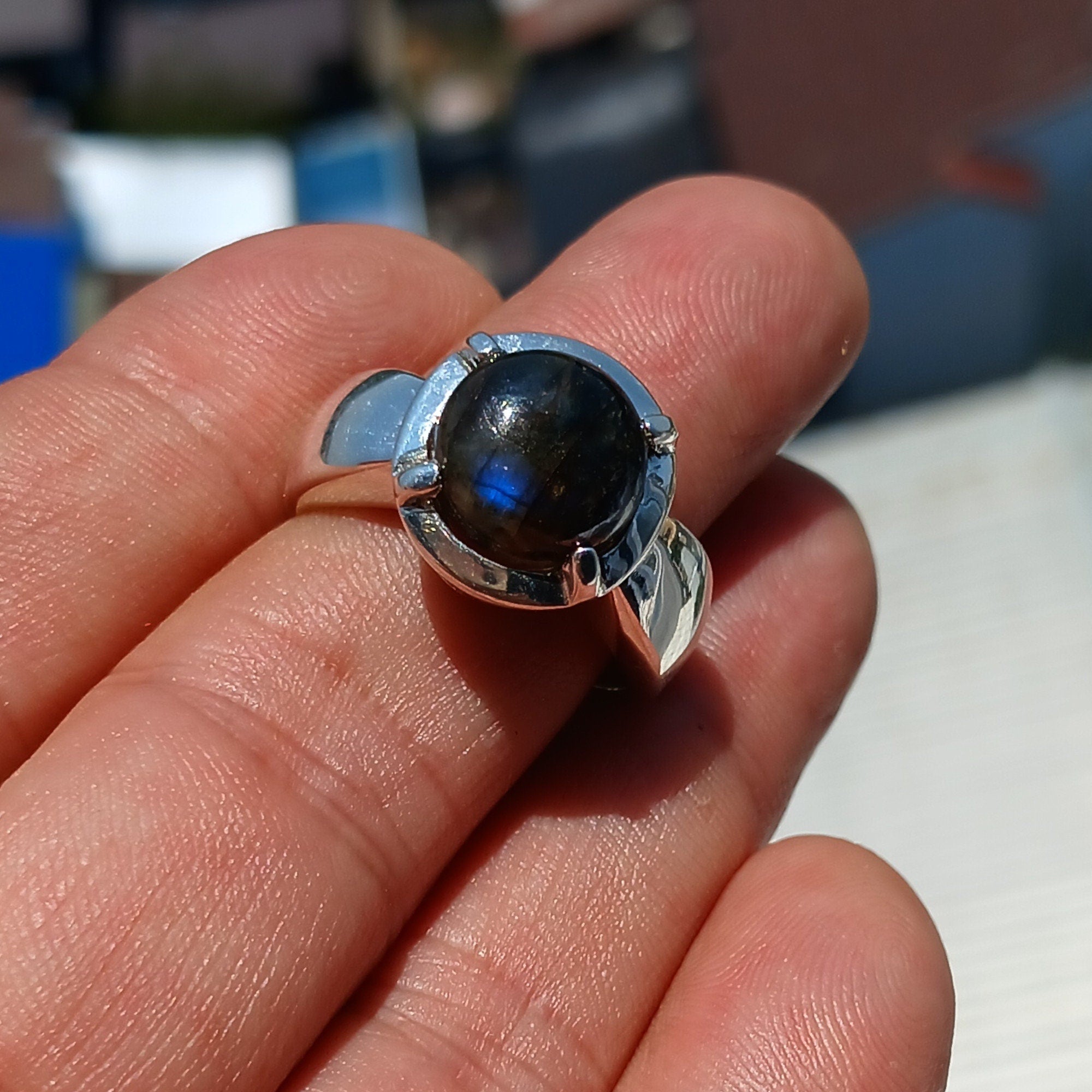 A handcrafted sterling silver ring featuring a round dark Labradorite stone, showcasing its unique design and craftsmanship.
