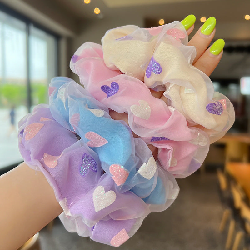 A stylish woman holding three colorful Sweet Love Mesh Double Layer Hair Ties, showcasing their vibrant colors and double layer design.