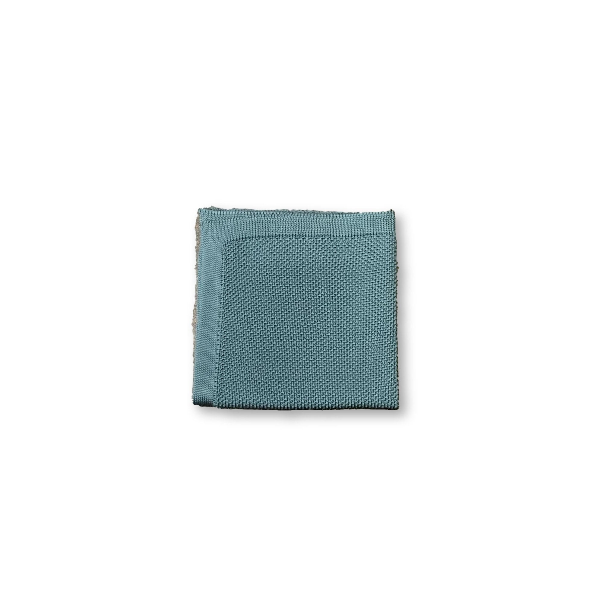 Teal knitted pocket square displayed elegantly, showcasing its vibrant color and soft texture.