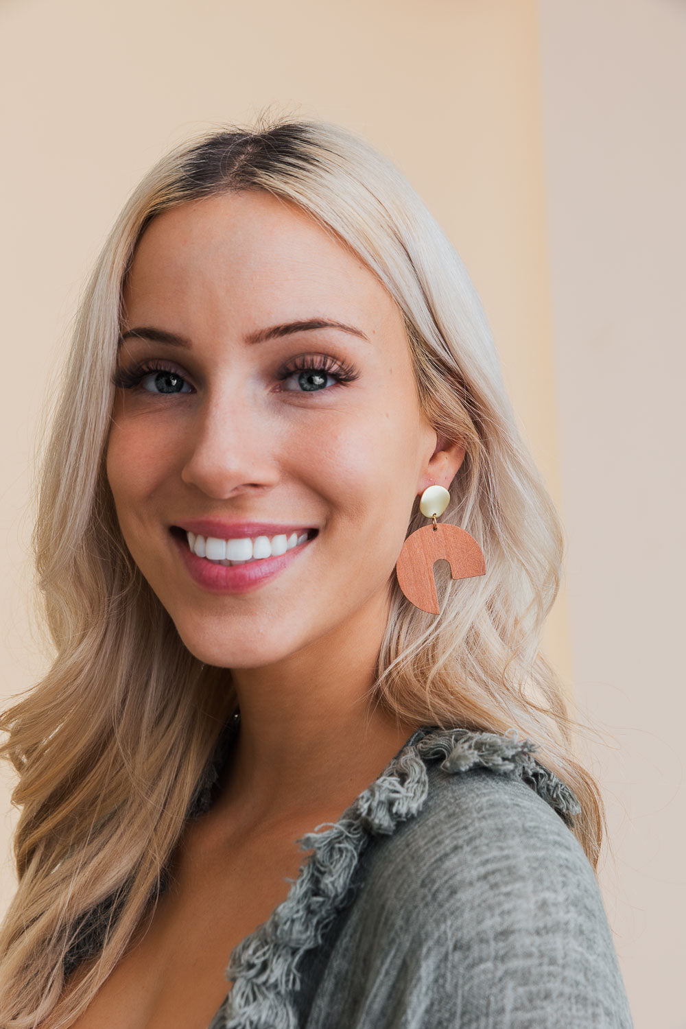 A pair of stylish wooden modern arch shaped earrings showcasing a contemporary design with a natural wood finish.