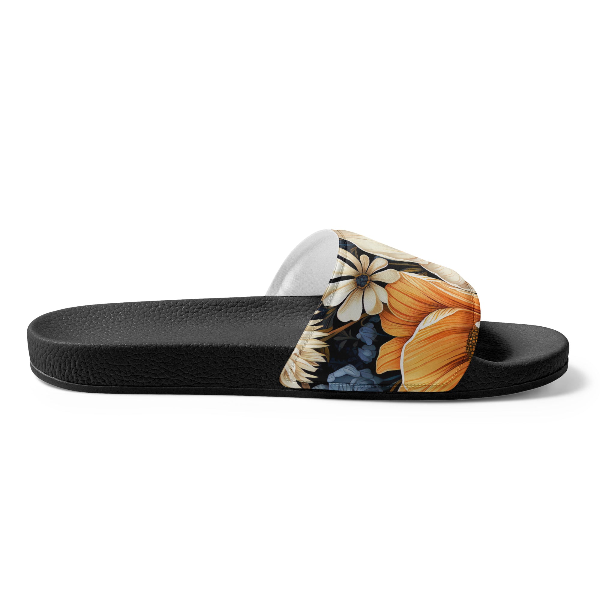 A pair of women's slides featuring a blue floral block print illustration, showcasing a cushioned upper strap and textured footbed.