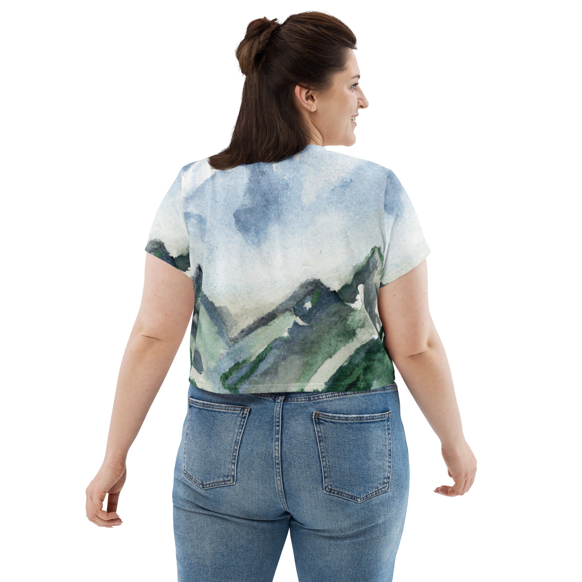 Womens Stretch Fit Crop Tee in green mountainside nature print, showcasing a vibrant landscape design against a blue sky.