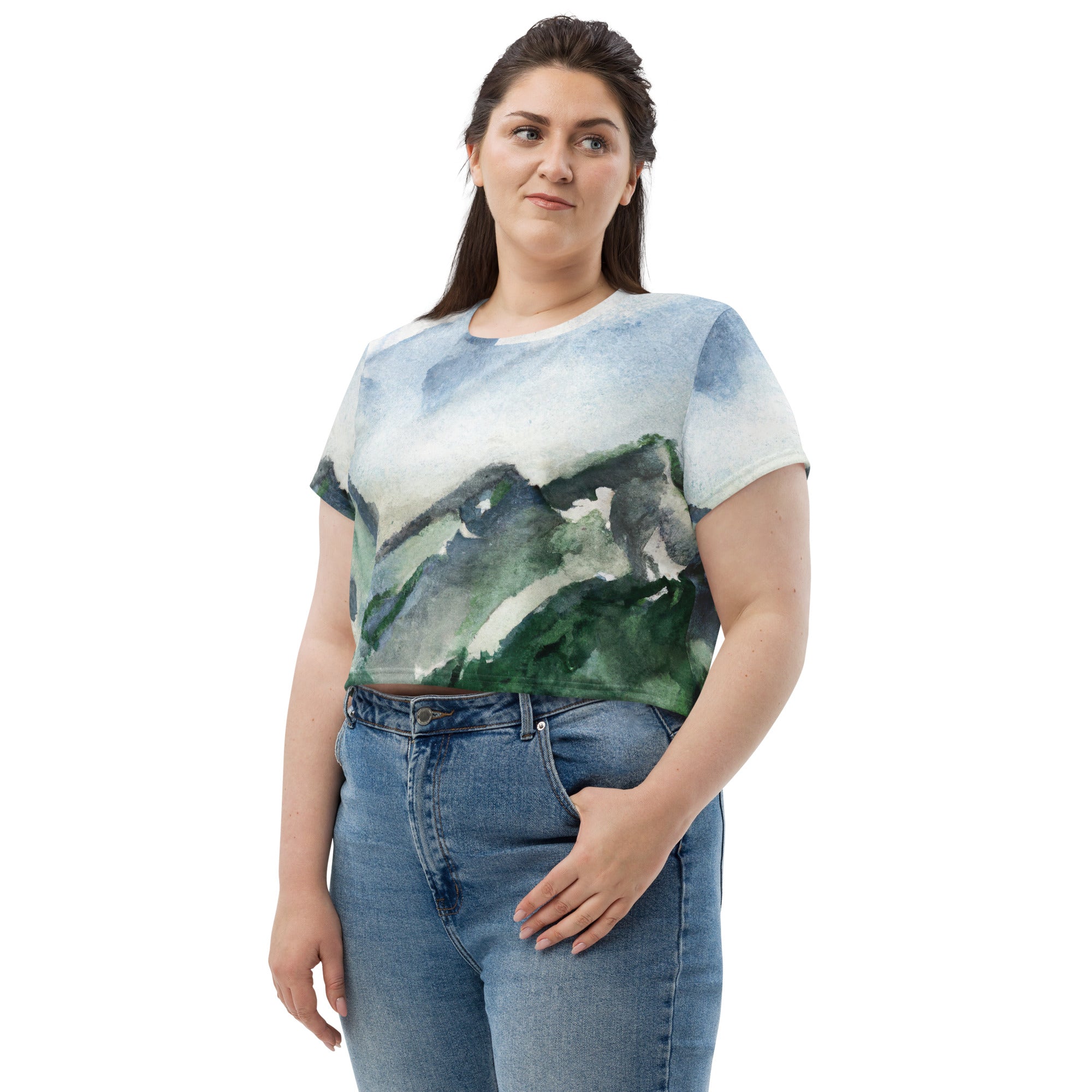 Womens Stretch Fit Crop Tee in green mountainside nature print, showcasing a vibrant landscape design against a blue sky.