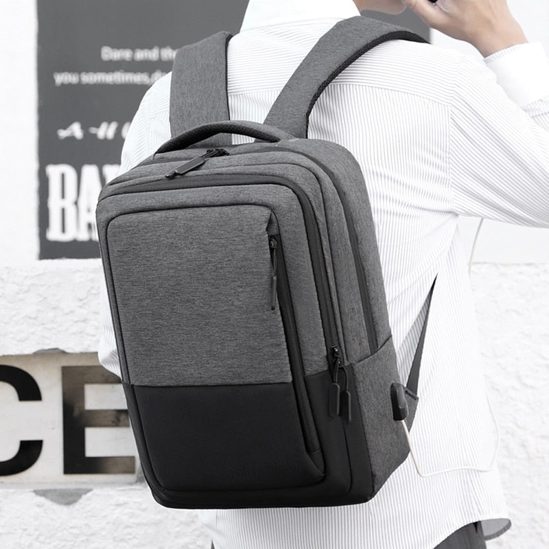 Multifunctional waterproof backpack for men with USB charging port, featuring a stylish patchwork design and multiple compartments.
