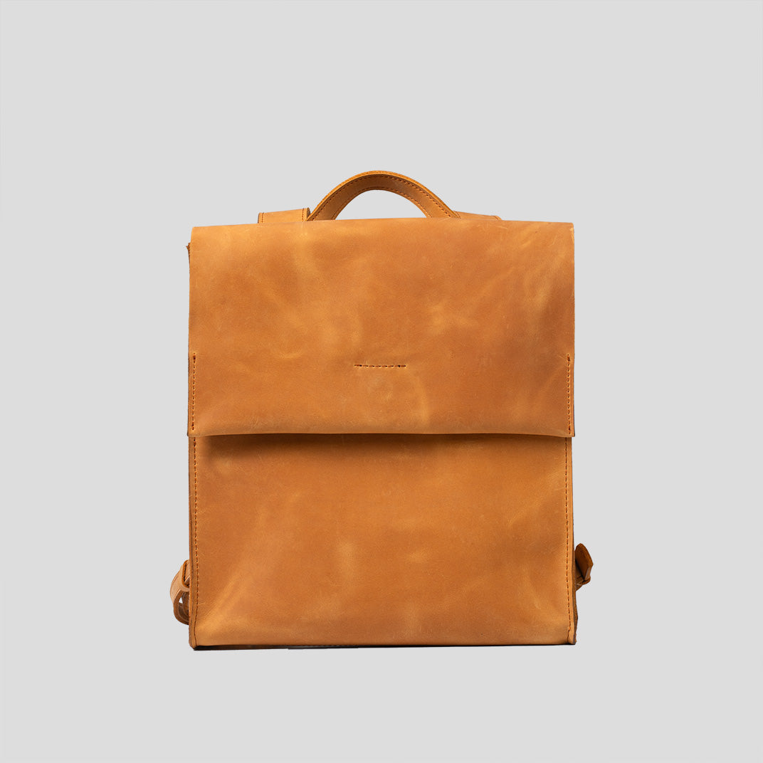 Stylish orange leather backpack with minimal design, featuring adjustable straps and magnetic closure.
