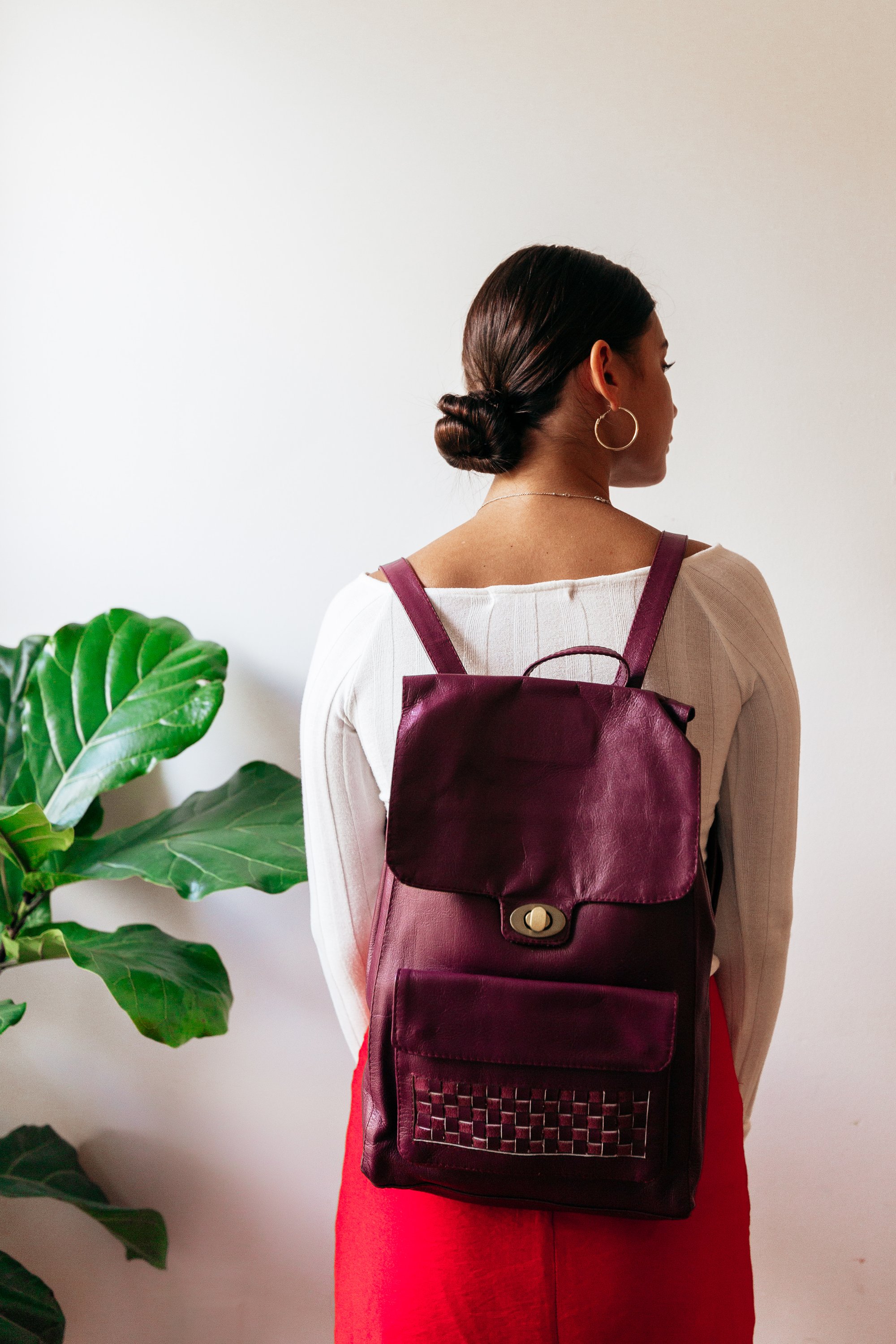 Magenta leather backpack with woven accent on front pocket, showcasing its stylish design and sustainable craftsmanship.
