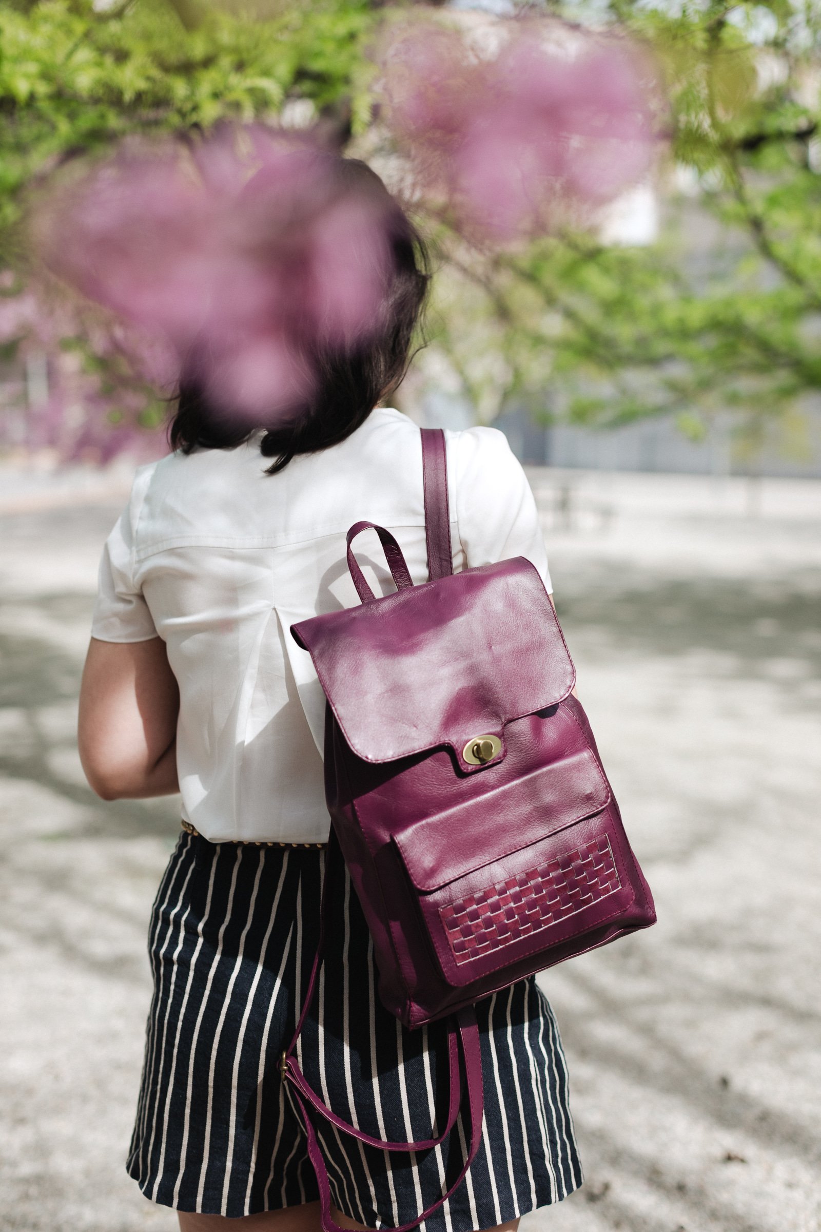 Magenta leather backpack with woven accent on front pocket, showcasing its stylish design and sustainable craftsmanship.