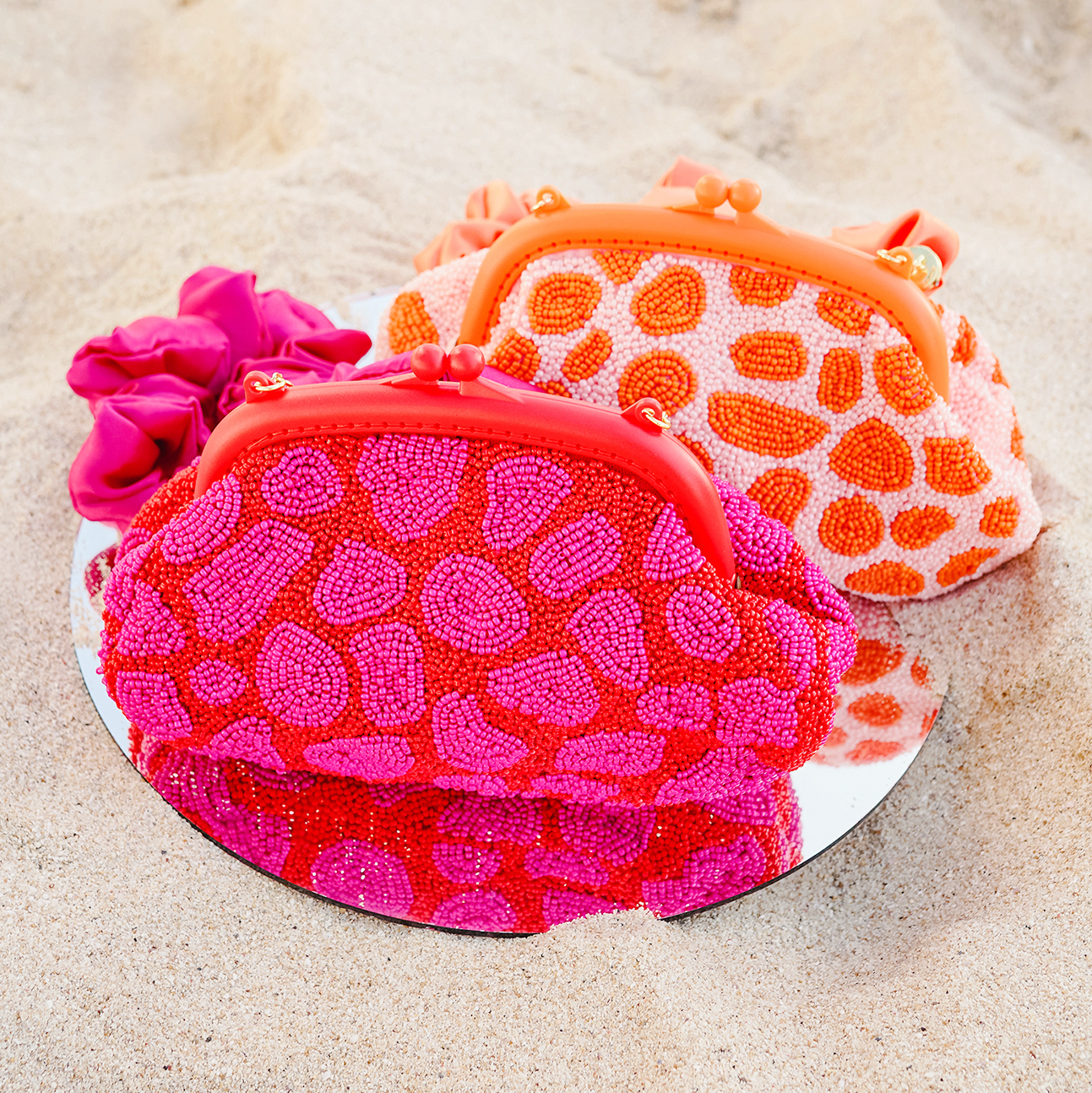 ARNOLDI JEAN Hand-beaded Clutch in vibrant red and pink, featuring intricate glass bead embellishments and a soft voluminous design with a satin scrunch handle.