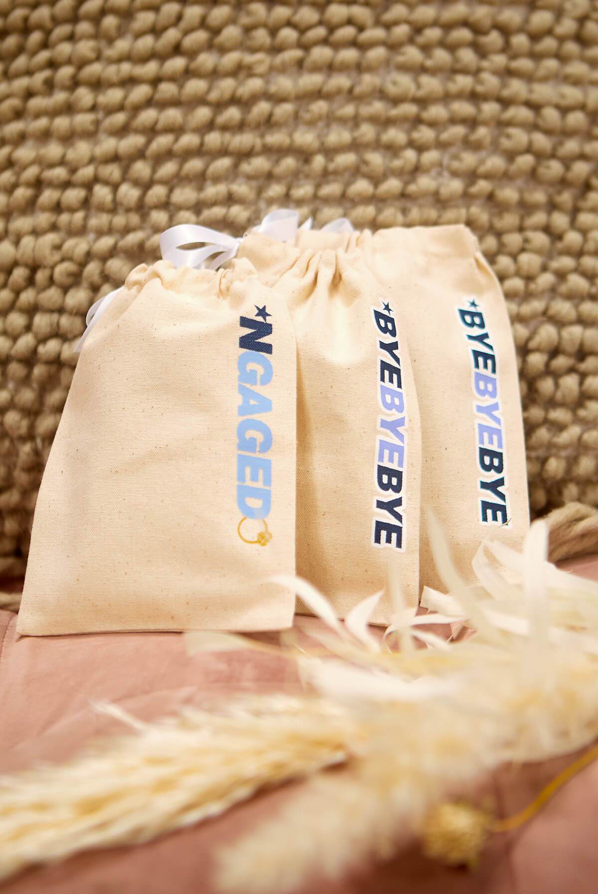 A collection of *NGAGED | ByeByeBye Boy Band Hangover Kit Bags, featuring fun phrases on stylish canvas pouches, perfect for celebrations.