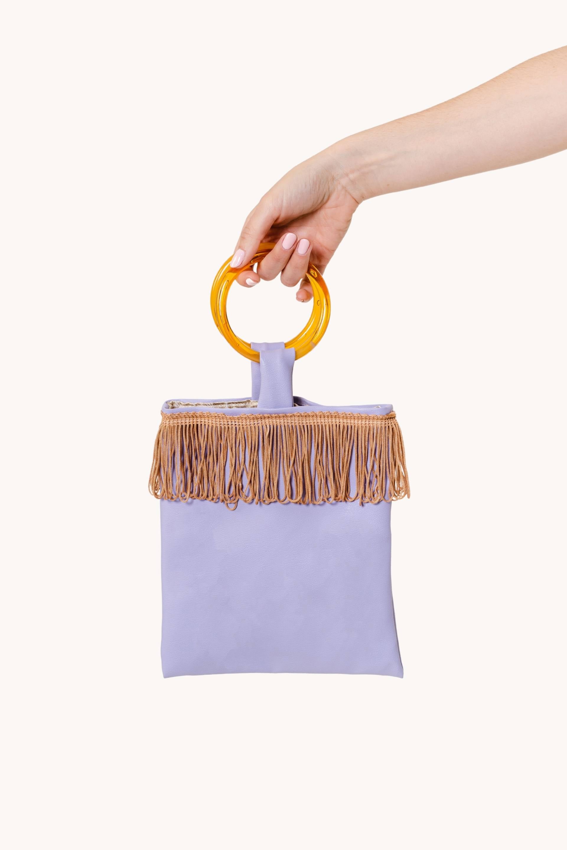 Lilac mini faux leather bag with amber resin handles and brown fringes, showcasing a stylish and trendy design.
