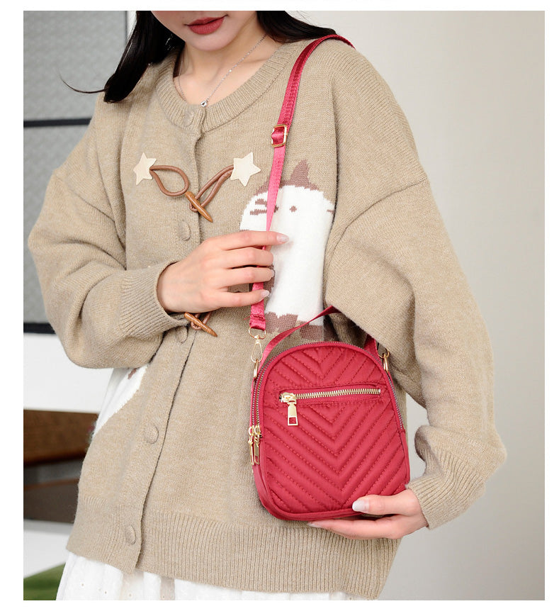 A stylish nylon quilted bag featuring multiple zipper pockets, adjustable strap, and gold-tone hardware.