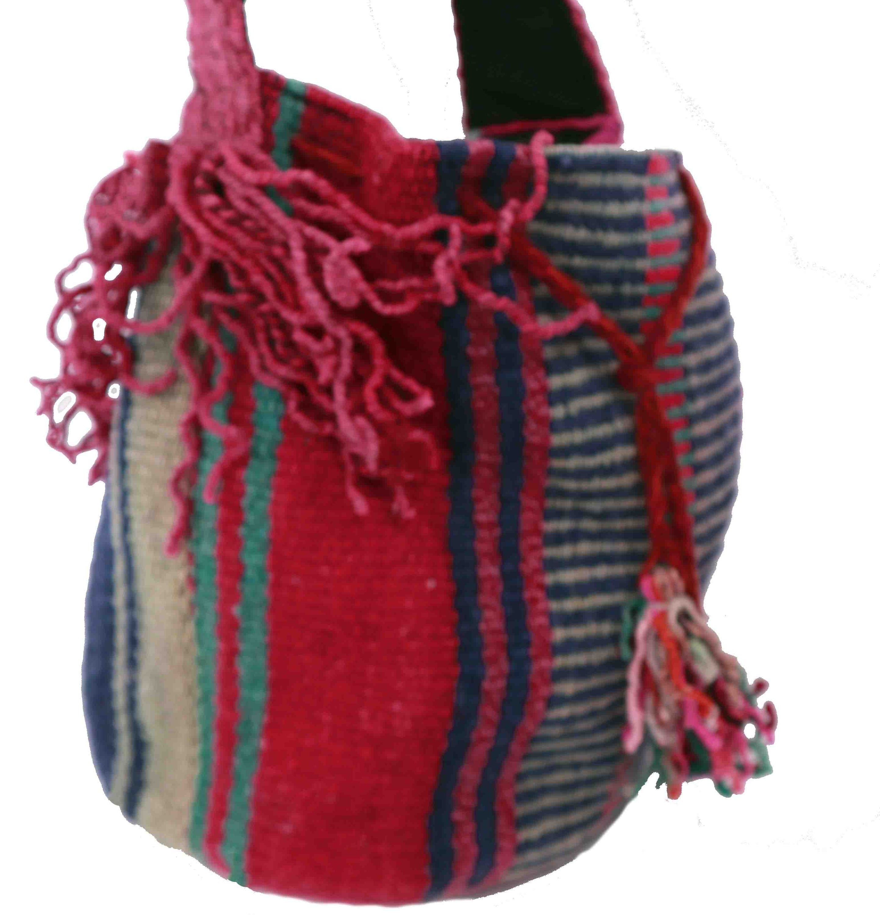 Vibrant raspberry red bucket-style crossbody bag with retro stripes and fringes, showcasing intricate basket weave textile.