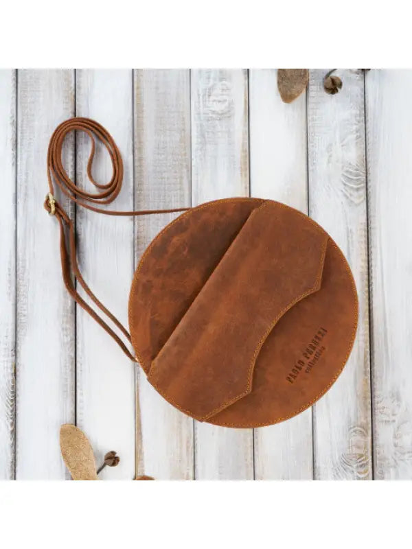 Round leather handbag made from aged natural hunter leather, featuring a zippered main compartment and multiple pockets for organization.