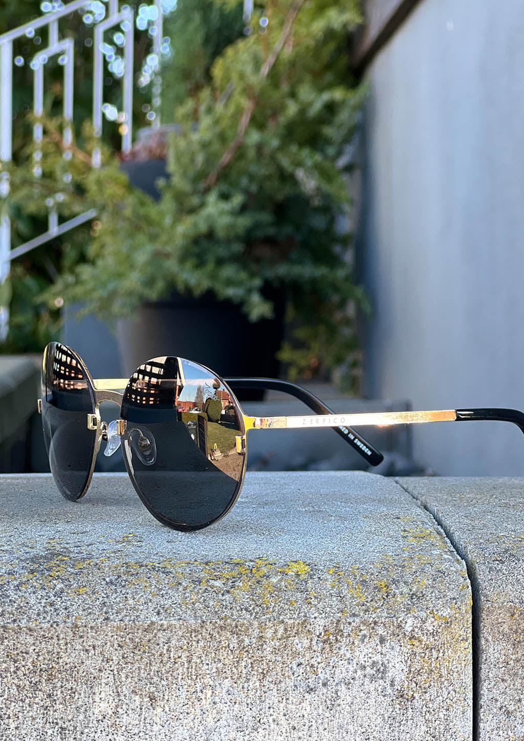 Luxurious titanium round sunglasses with 24K gold plating and interchangeable lenses, showcasing a stylish and elegant design.