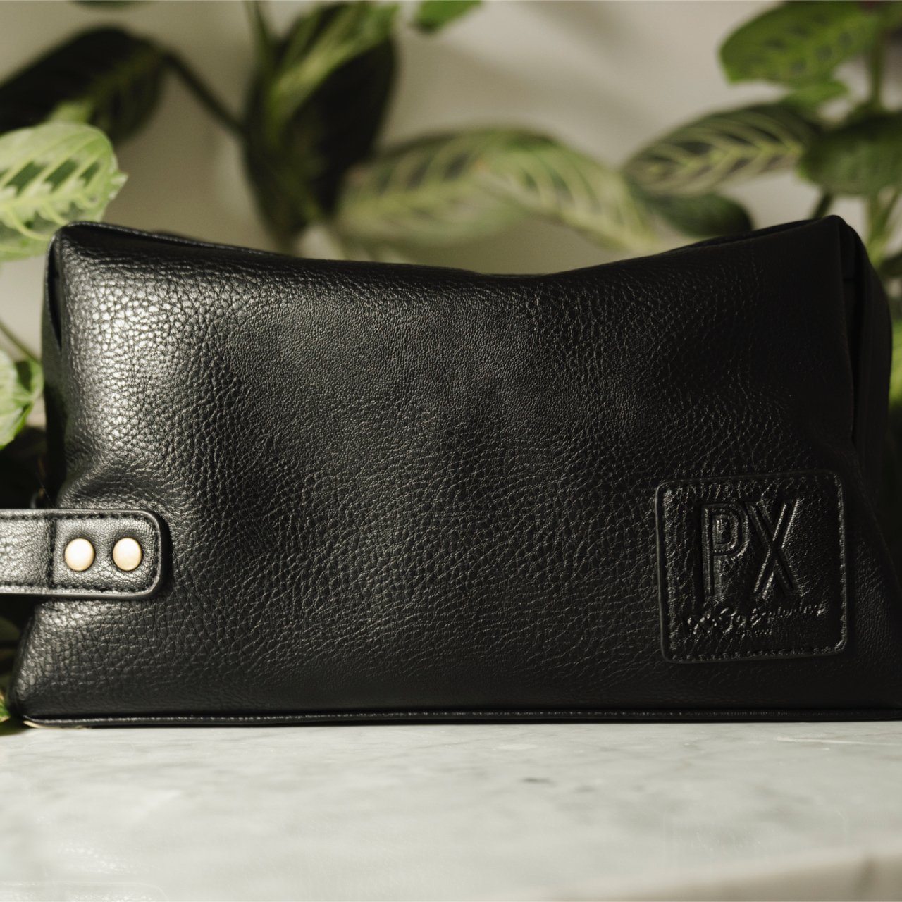 Black leather toiletry bag on marble.