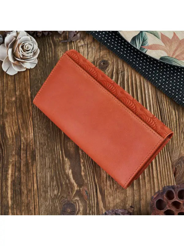Natural leather women's wallet in red, green, and orange with geometric embossed pattern and compartments for cards and cash.