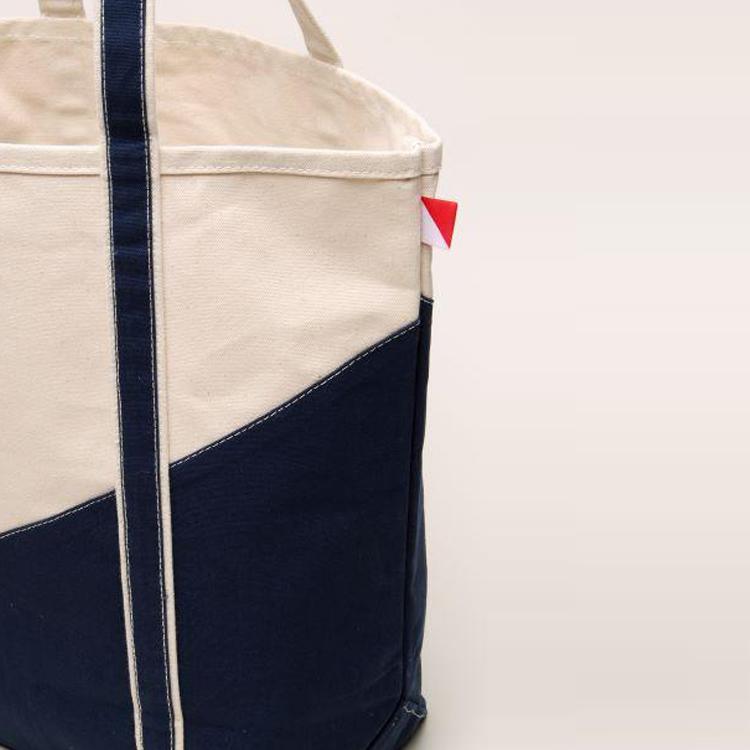 A large contemporary tote bag featuring a diagonal sail design, reinforced handles, and multiple interior pockets for organization.