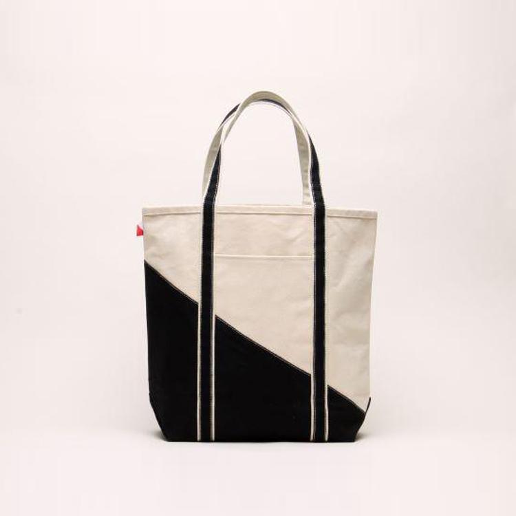 A large contemporary tote bag featuring a diagonal sail design, reinforced handles, and multiple interior pockets for organization.