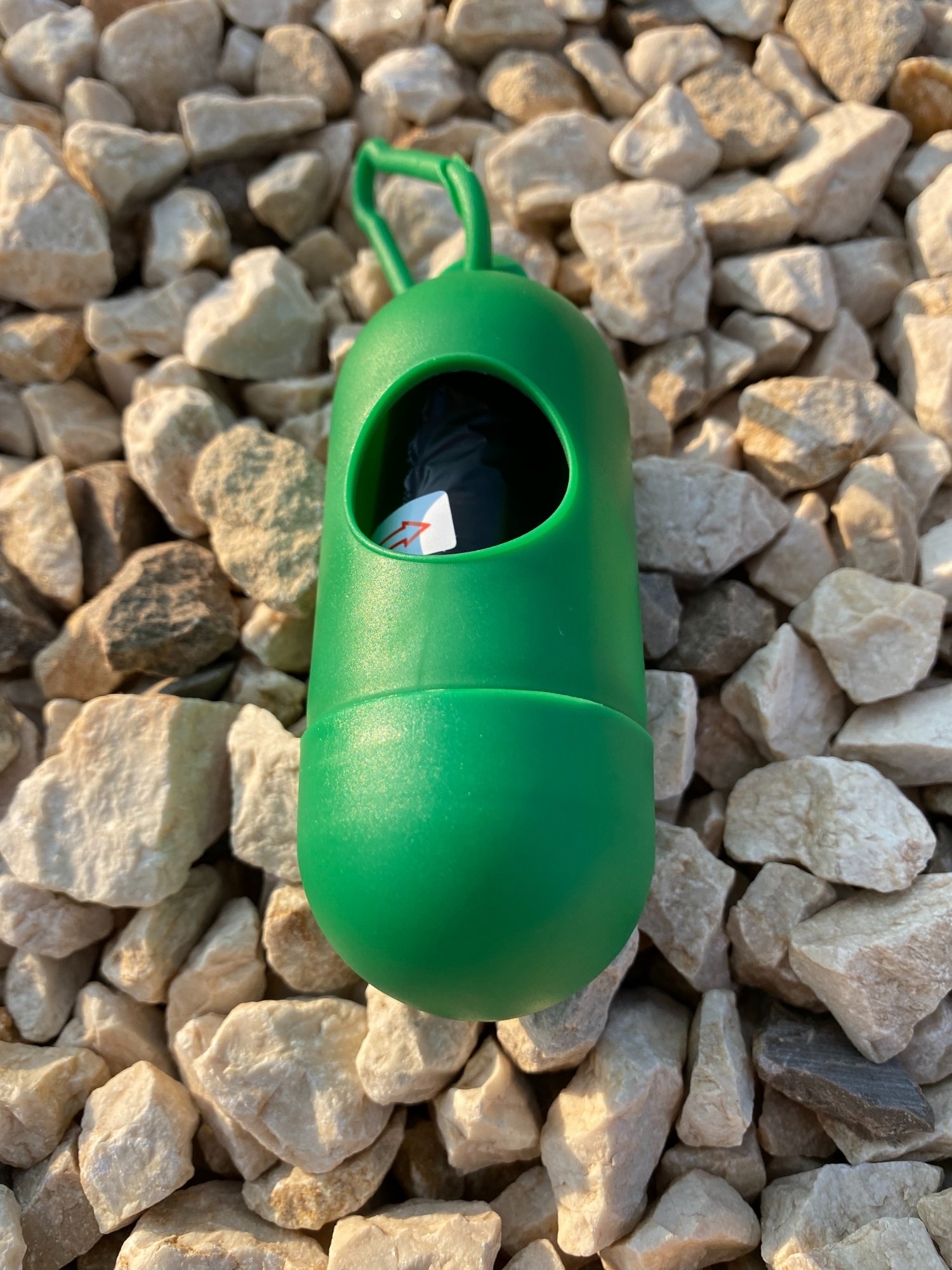 Dog Poop Bag Dispenser in vibrant colors with bags attached, showcasing its compact design and carabiner clip.