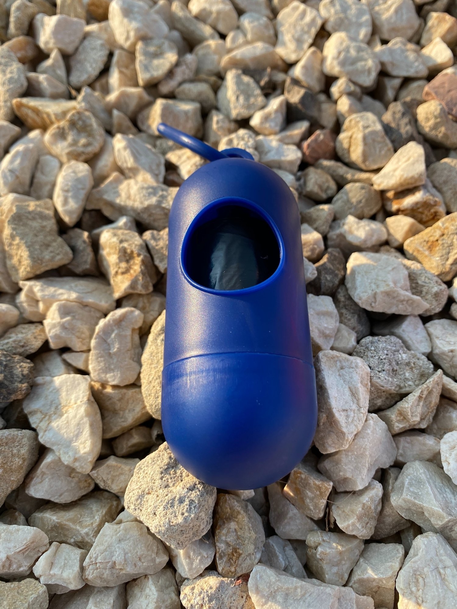Dog Poop Bag Dispenser in vibrant colors with bags attached, showcasing its compact design and carabiner clip.
