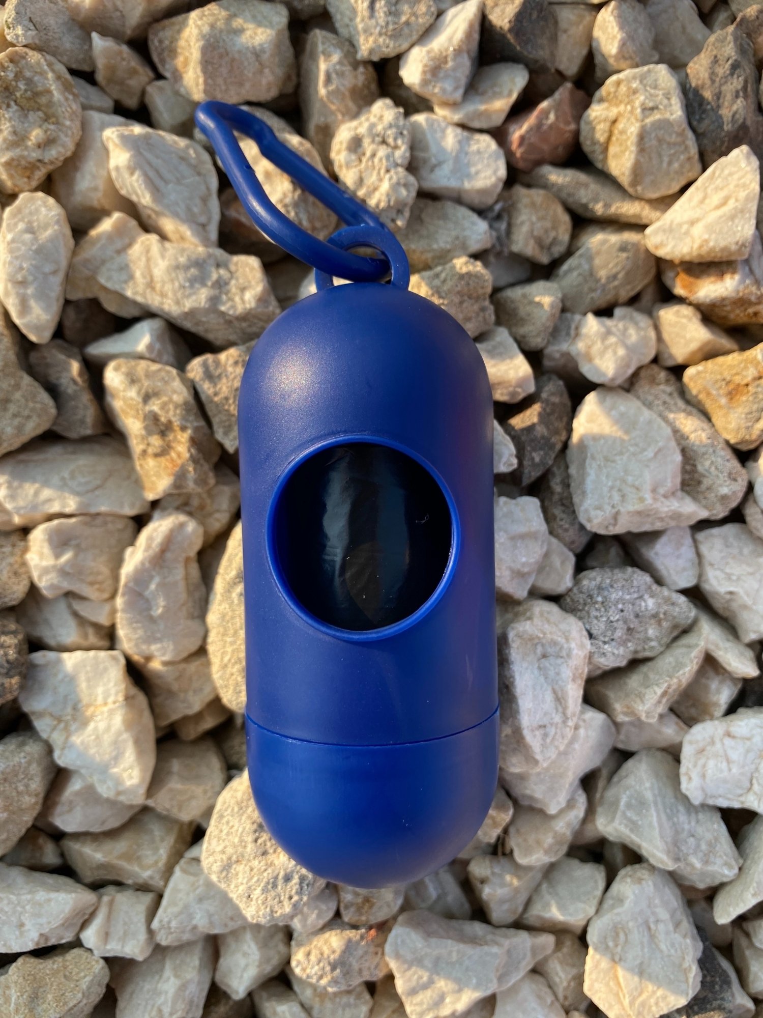 Dog Poop Bag Dispenser in vibrant colors with bags attached, showcasing its compact design and carabiner clip.