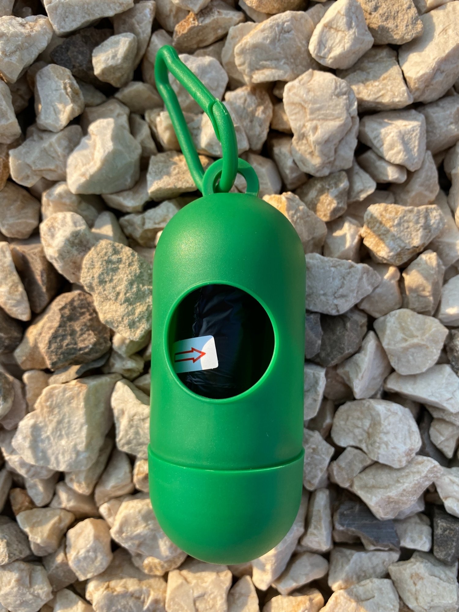 Dog Poop Bag Dispenser in vibrant colors with bags attached, showcasing its compact design and carabiner clip.