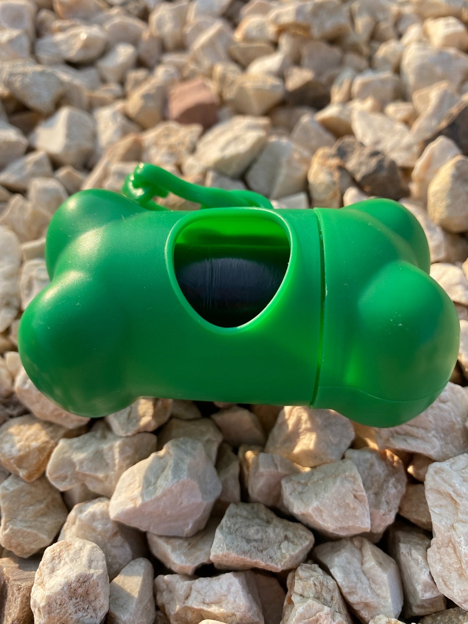 DogBone Poop Bag Dispenser in various colors with attached bags, featuring a plastic carabiner clip for leash attachment.