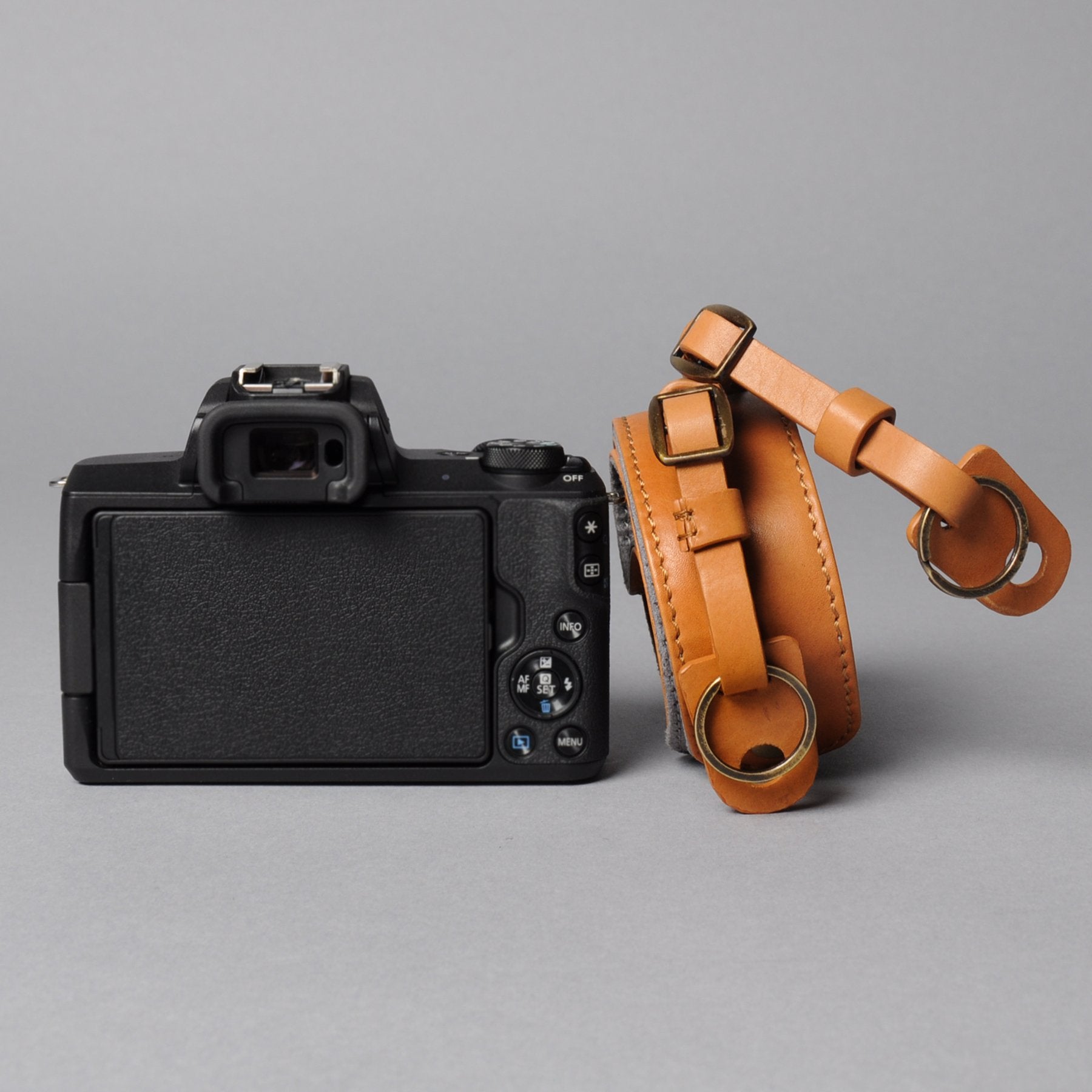 A stylish DSLR camera leather strap made from durable harness leather, featuring adjustable length and antique brass hardware.