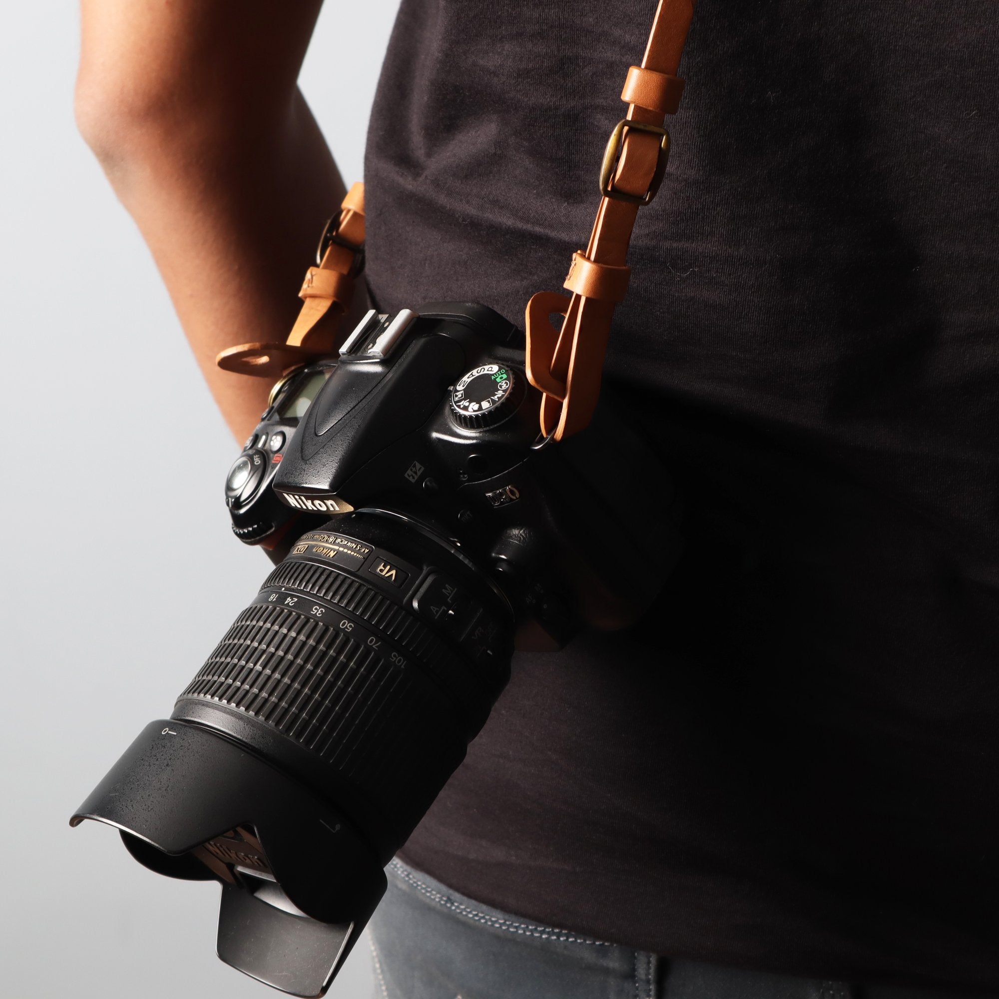 A stylish DSLR camera leather strap made from durable harness leather, featuring adjustable length and antique brass hardware.