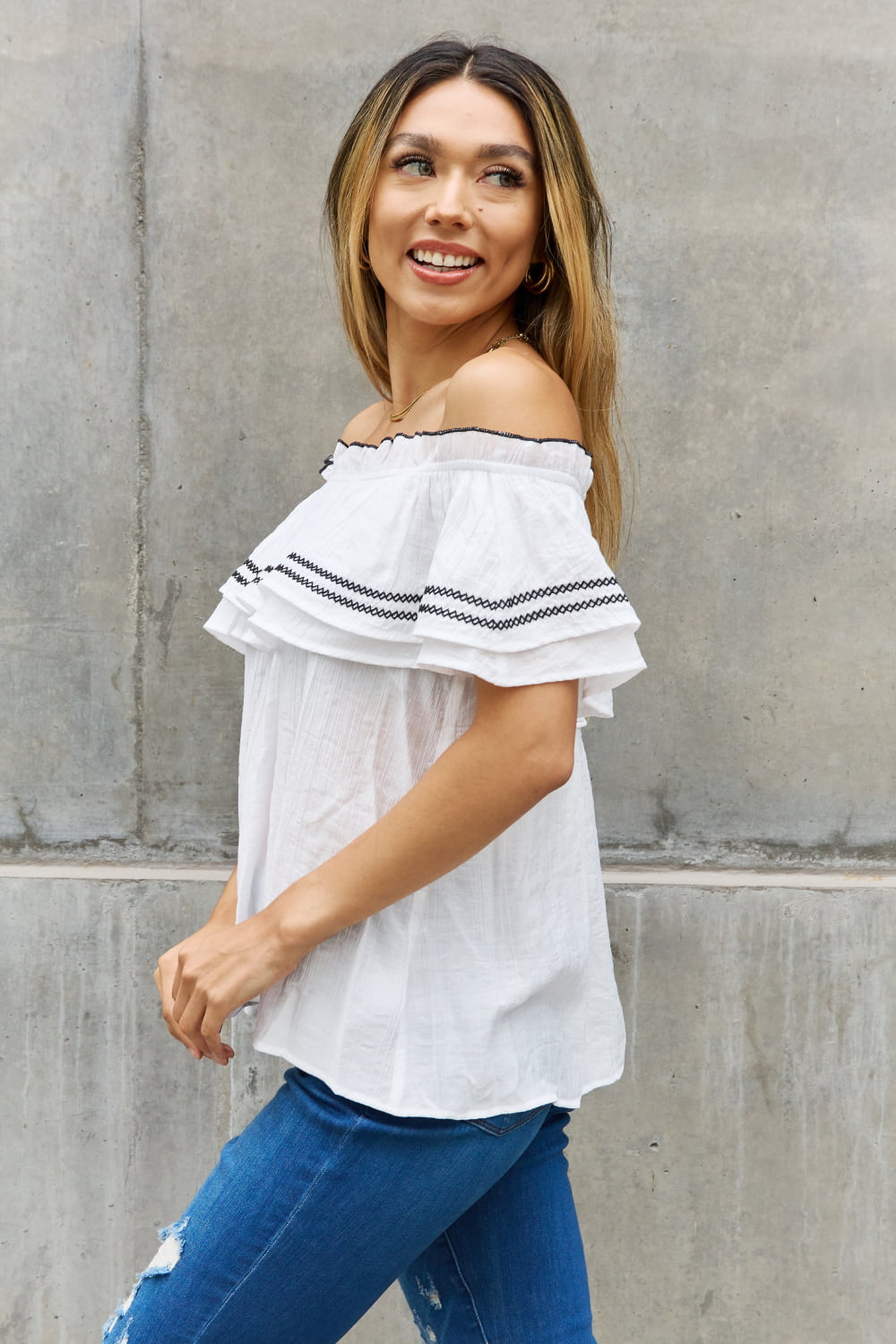A stylish full size off-the-shoulder ruffle blouse featuring intricate embroidery and flutter sleeves, perfect for a chic look.