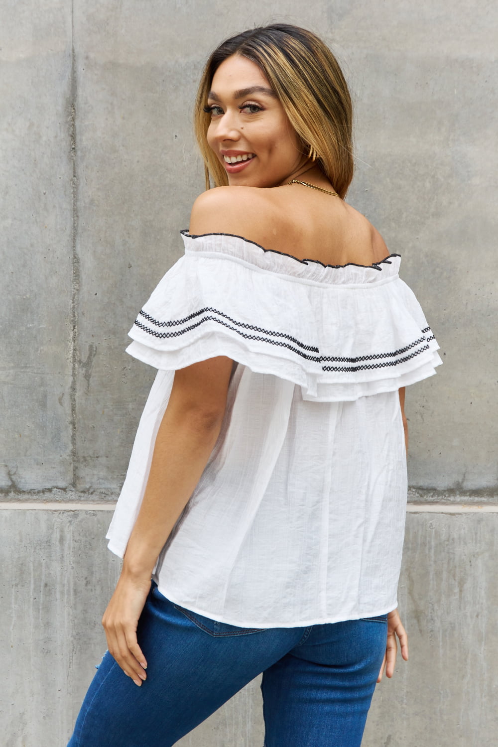 A stylish full size off-the-shoulder ruffle blouse featuring intricate embroidery and flutter sleeves, perfect for a chic look.