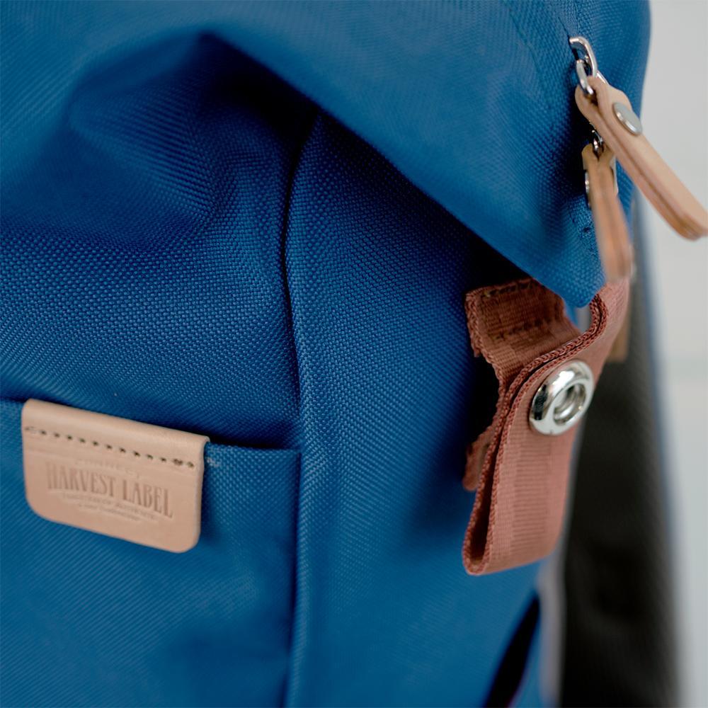 Highline Daypack in various colors with leather accents, showcasing its sleek design and multiple pockets.
