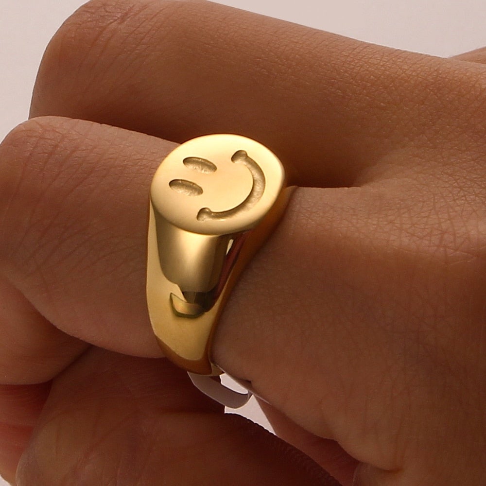 A trendy 18K gold plated stainless steel ring featuring a playful smiley face design, perfect for women.