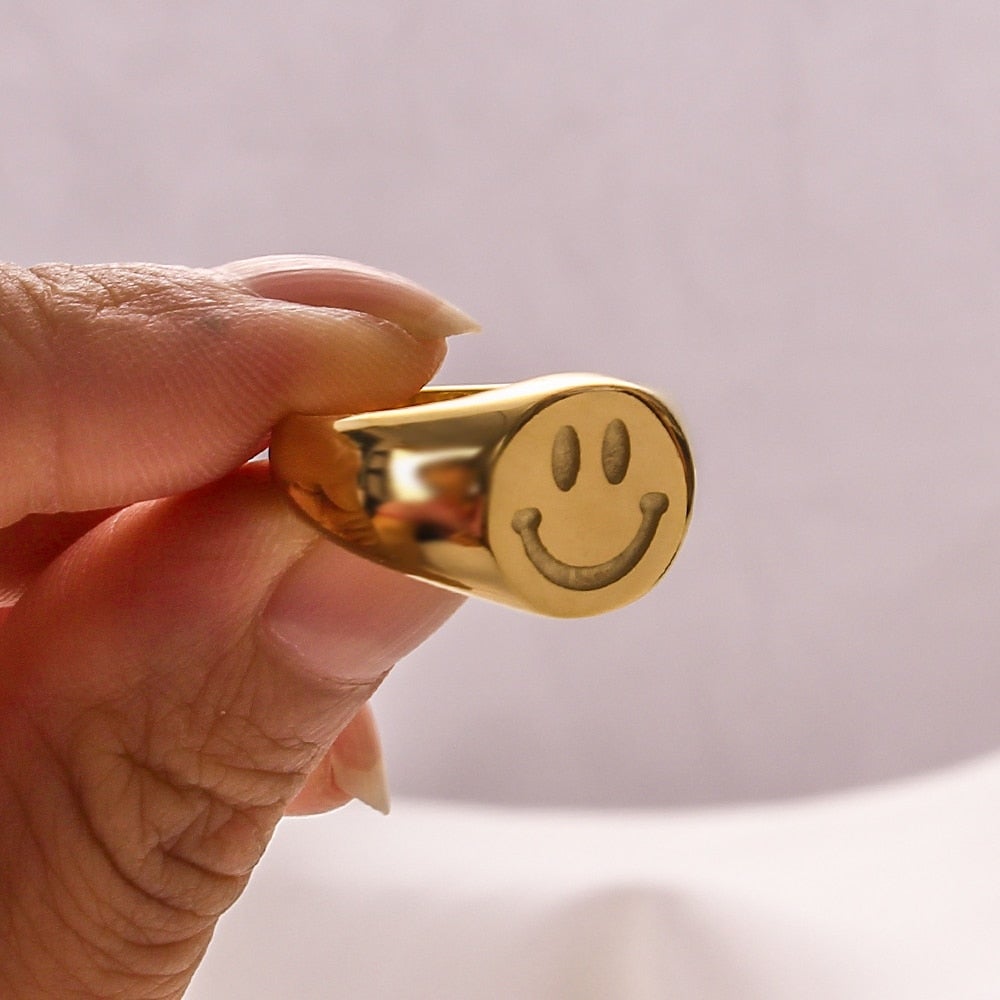 A trendy 18K gold plated stainless steel ring featuring a playful smiley face design, perfect for women.