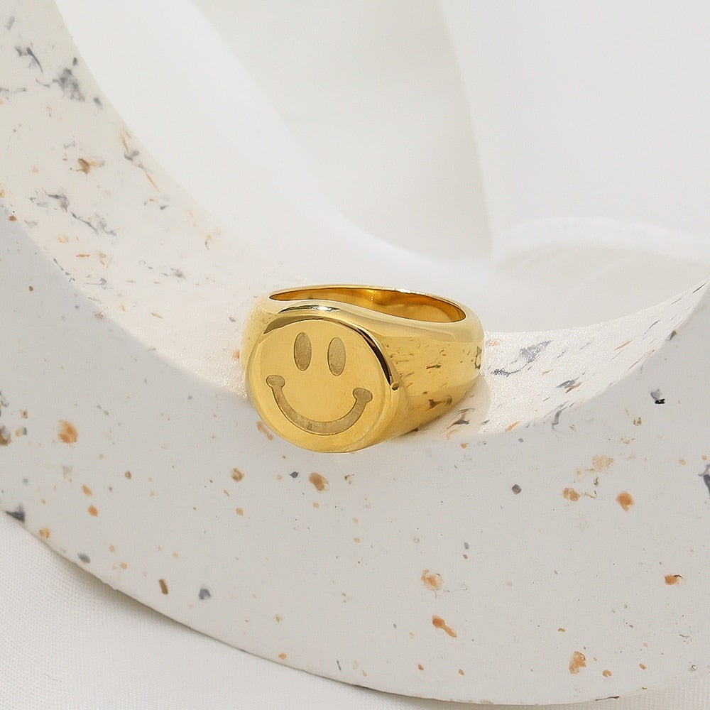 A trendy 18K gold plated stainless steel ring featuring a playful smiley face design, perfect for women.