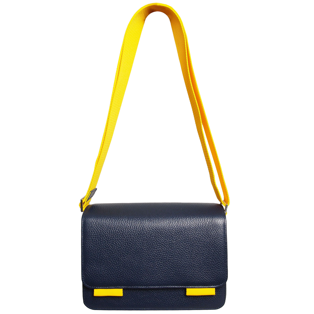 A stylish blue pebbled leather crossbody bag with a magnetic flap closure and a contrasting wide vinyl strap, showcasing its elegant design and craftsmanship.