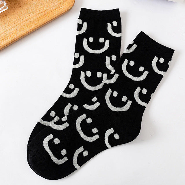 A pair of women's socks featuring a cheerful cartoon smiling face design, made from soft cotton material.