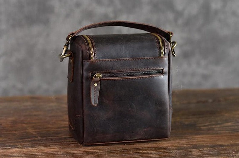 The Calista small leather camera bag made from full-grain leather, featuring a zippered back pocket and adjustable shoulder strap.