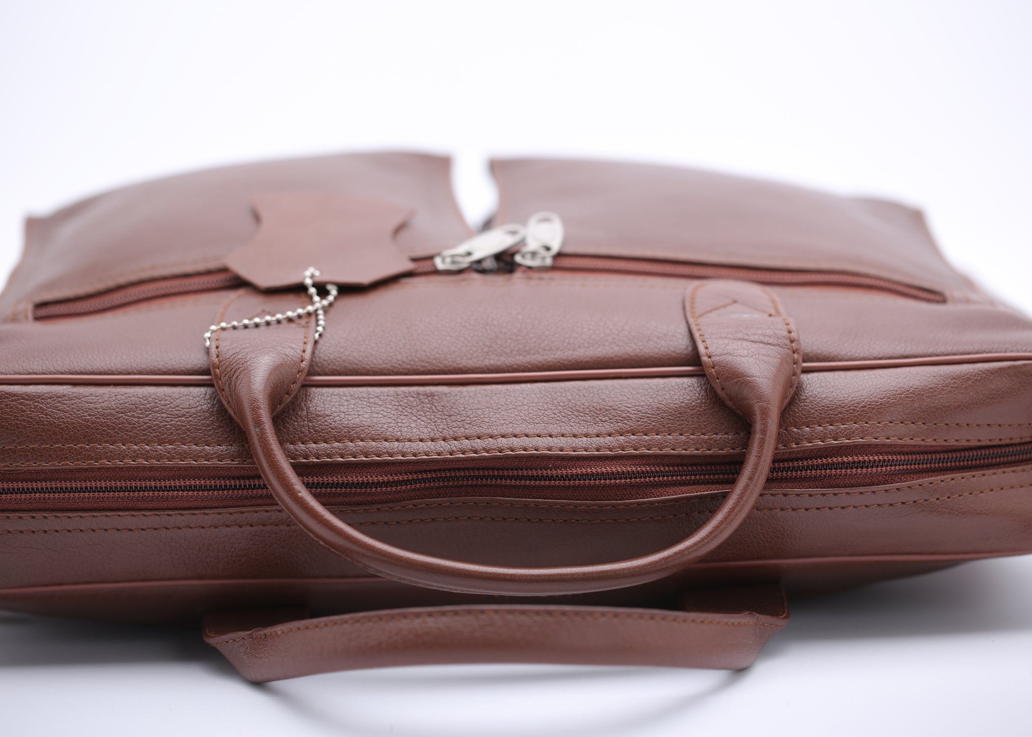 Tan leather briefcase bag with multiple compartments and adjustable shoulder strap, designed for professionals.