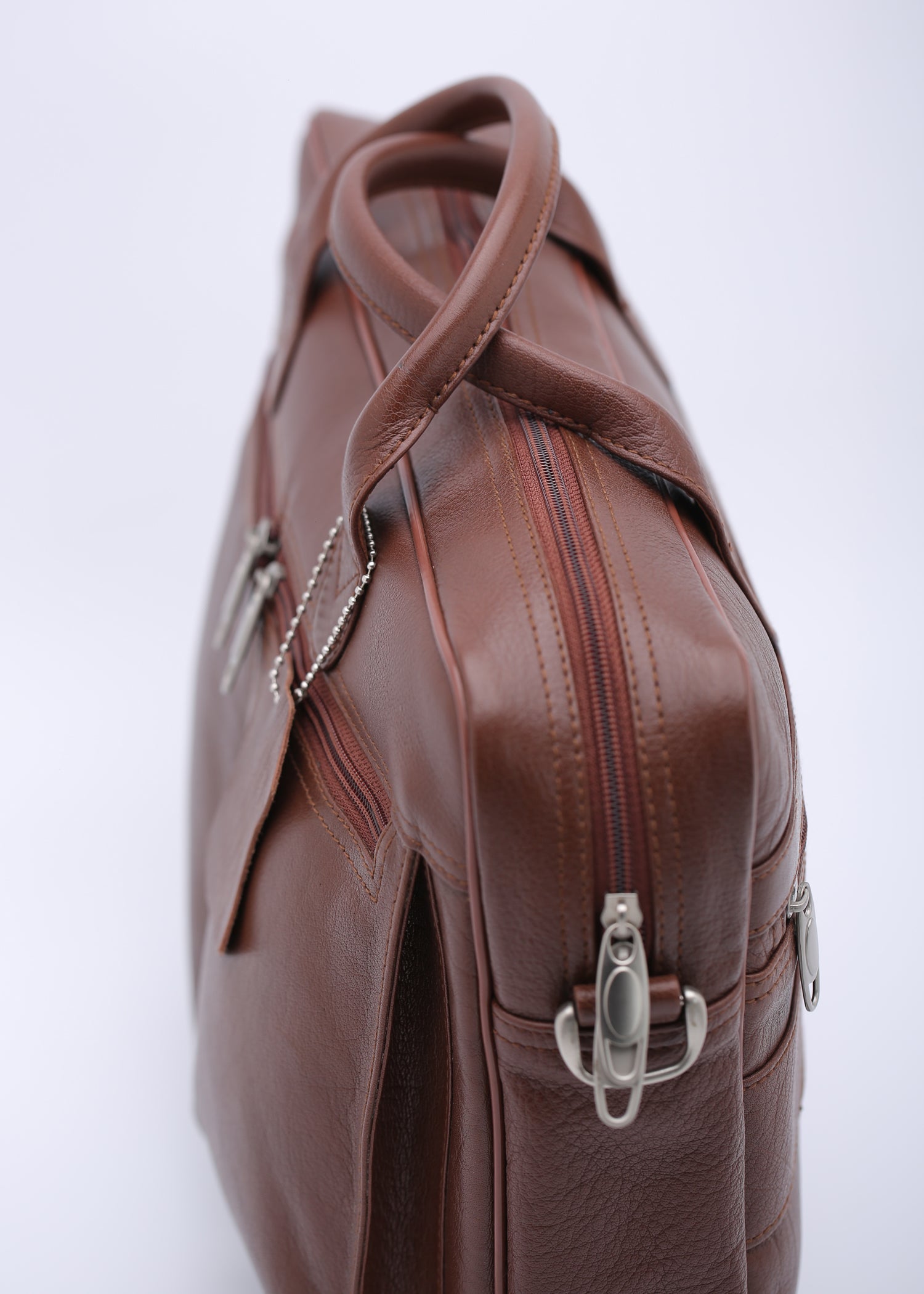 Tan leather briefcase bag with multiple compartments and adjustable shoulder strap, designed for professionals.