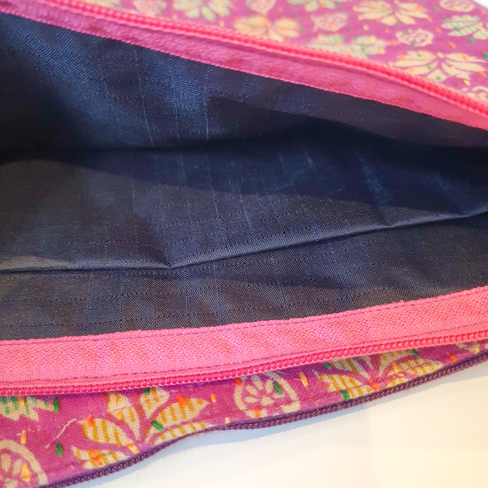 Upcycled sari clutch featuring vibrant colors and intricate kantha stitch embroidery, perfect for carrying essentials.