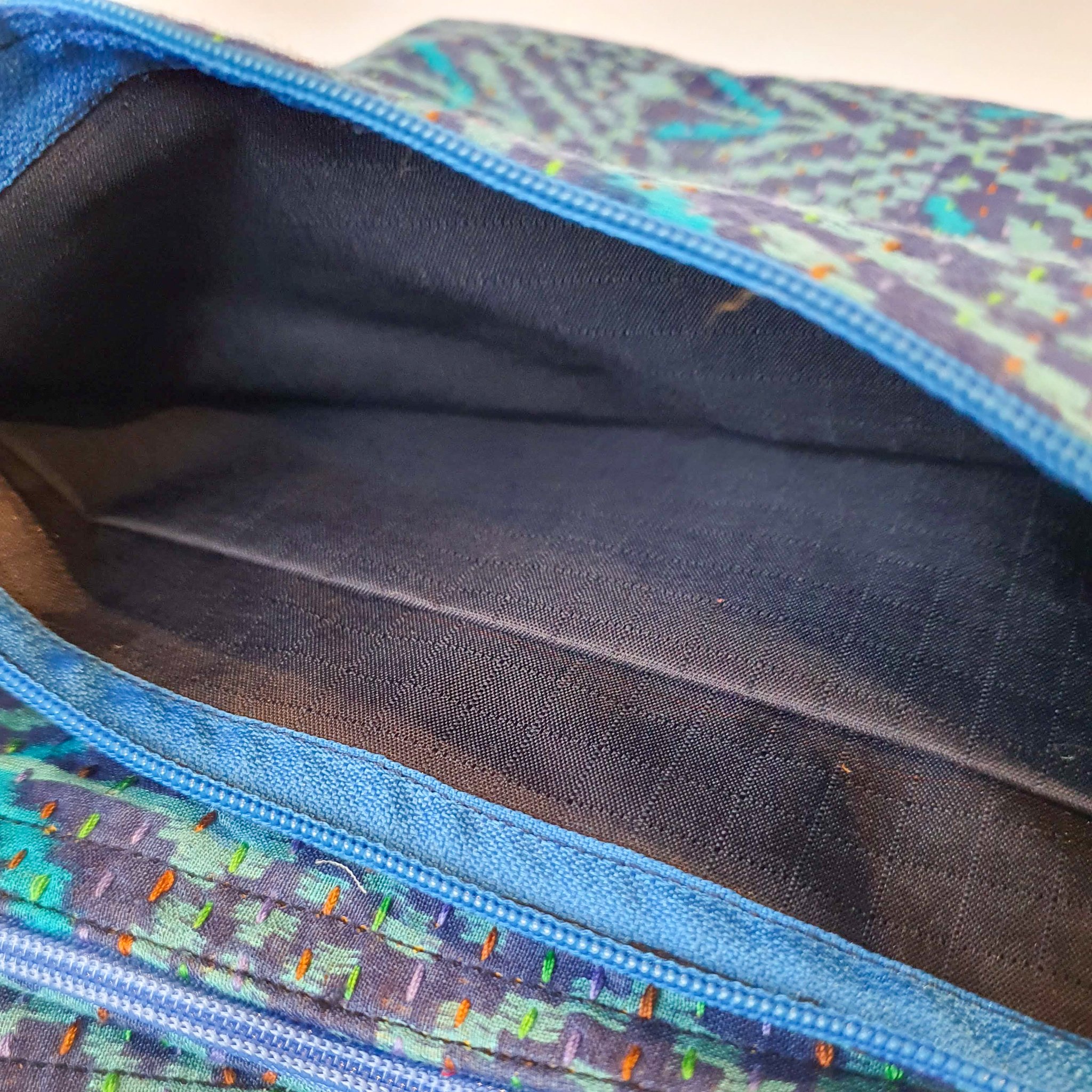 Upcycled sari clutch featuring vibrant colors and intricate kantha stitch embroidery, perfect for carrying essentials.