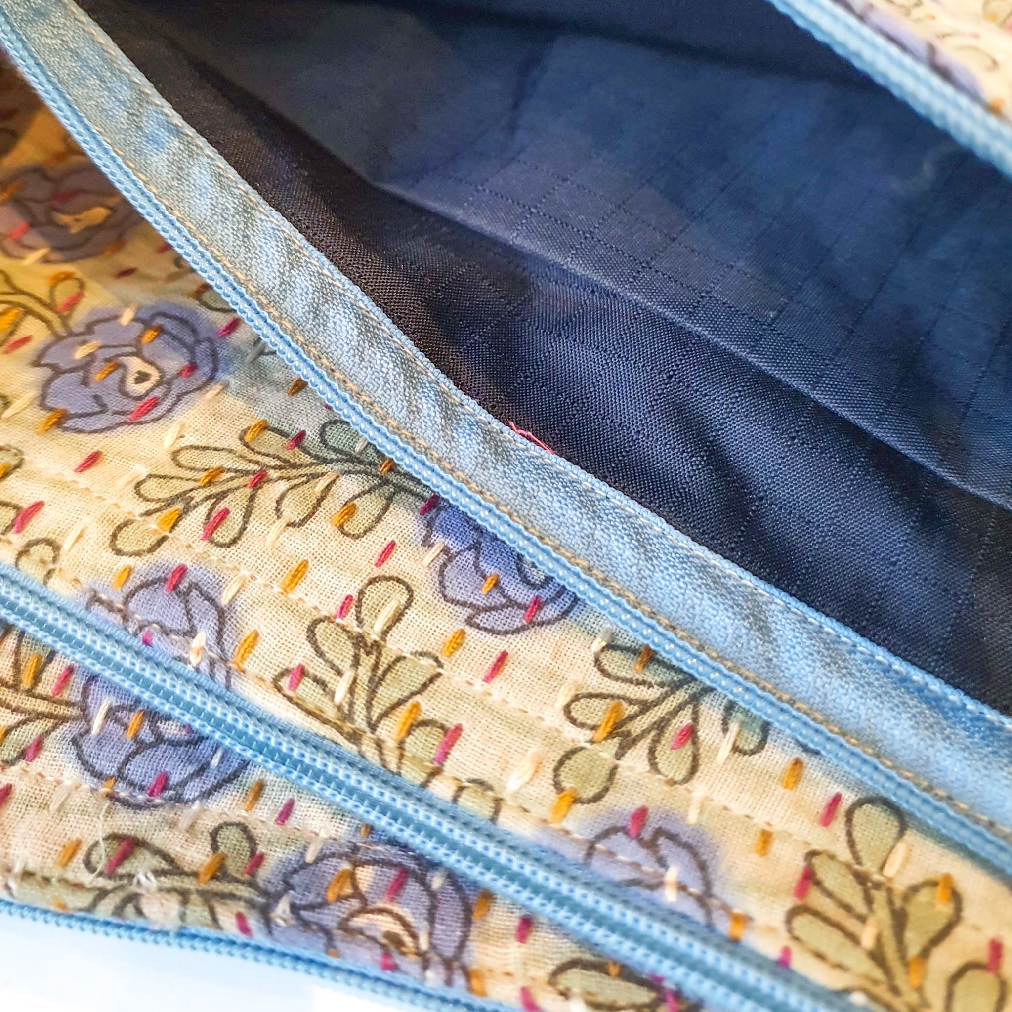 Upcycled sari clutch featuring vibrant colors and intricate kantha stitch embroidery, perfect for carrying essentials.