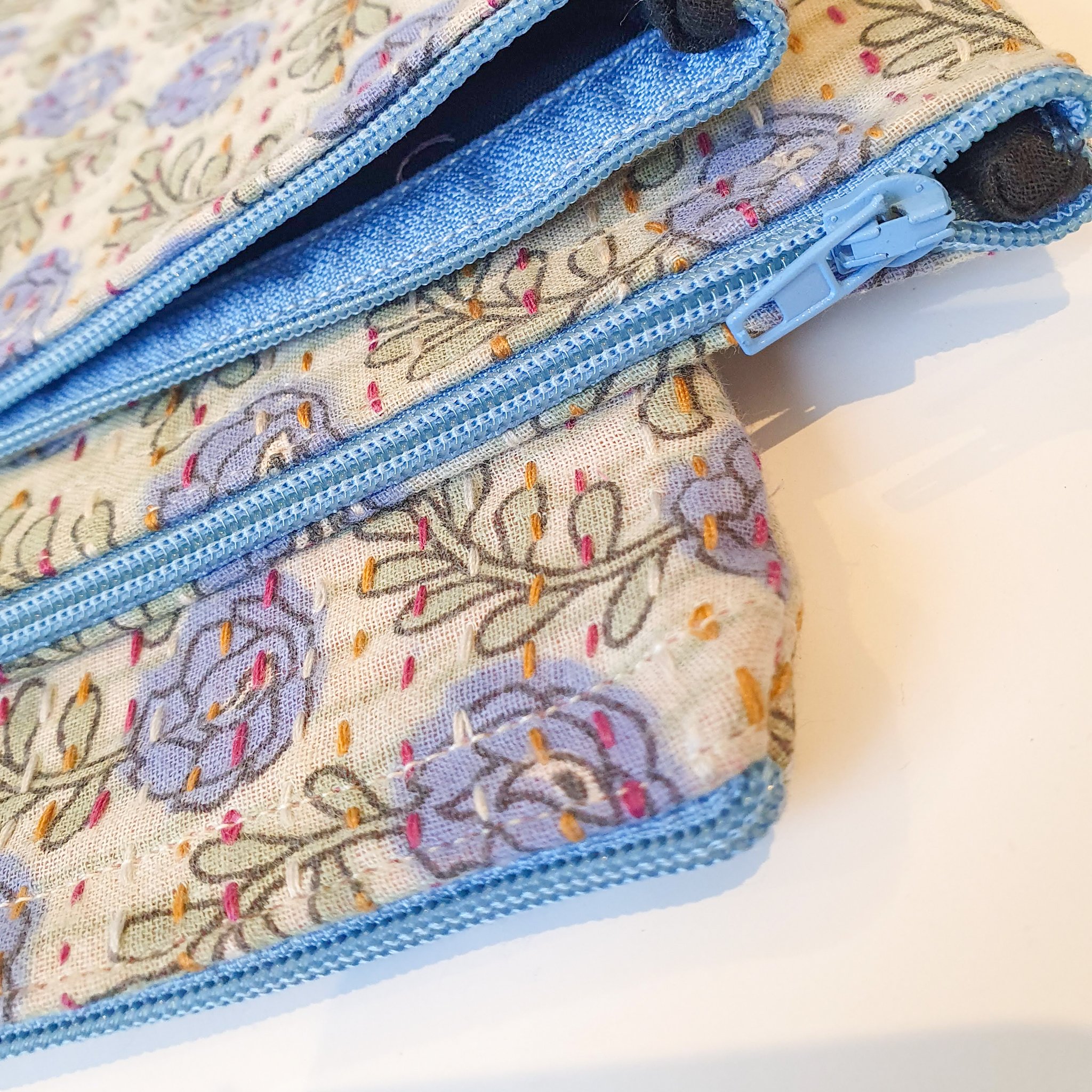 Upcycled sari clutch featuring vibrant colors and intricate kantha stitch embroidery, perfect for carrying essentials.