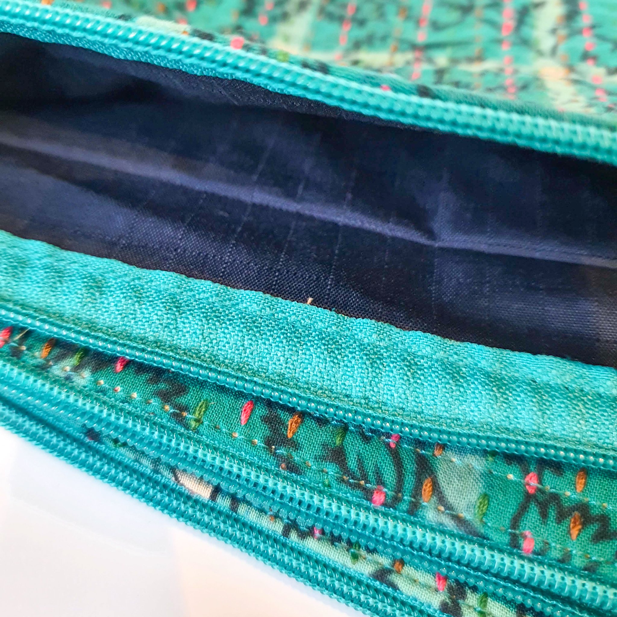 Upcycled sari clutch featuring vibrant colors and intricate kantha stitch embroidery, perfect for carrying essentials.