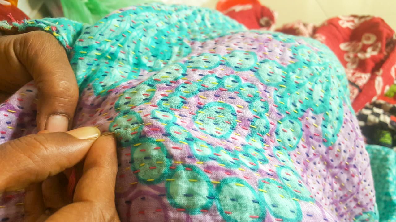 Upcycled sari clutch featuring vibrant colors and intricate kantha stitch embroidery, perfect for carrying essentials.