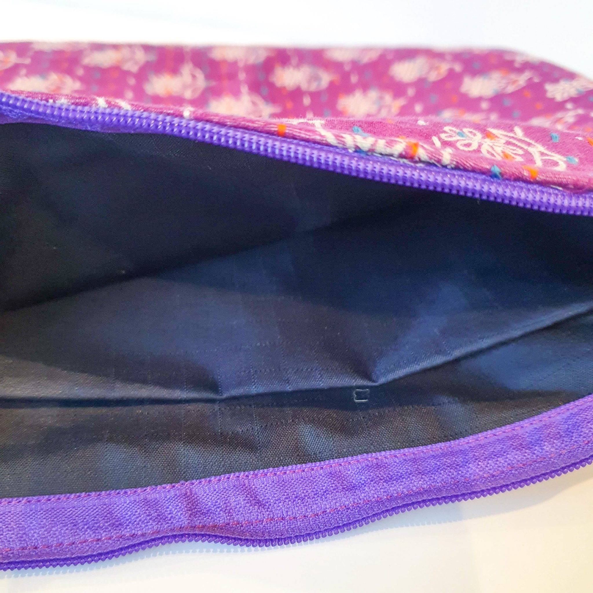 Upcycled sari clutch featuring vibrant colors and intricate kantha stitch embroidery, perfect for carrying essentials.