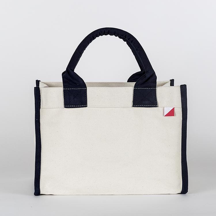 Village Tote Bag with rolled canvas handles and structured design, featuring three interior pockets for organization.