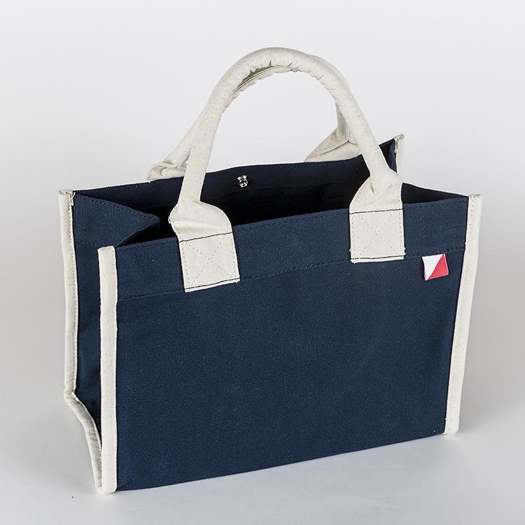 Village Tote Bag with rolled canvas handles and structured design, featuring three interior pockets for organization.